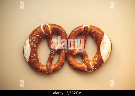 two freshly baked pretzels close-up, isolated on a beige background. Stock Photo
