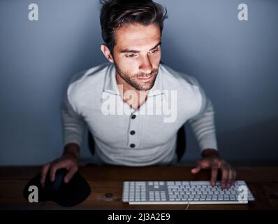 Working late. Shot of a handsome young man working late on a computer. Stock Photo