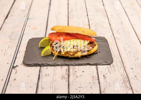 Chopped roast beef sandwich, lettuce strips, tomato slices, a squeeze of lime and toasted muffin bread Stock Photo