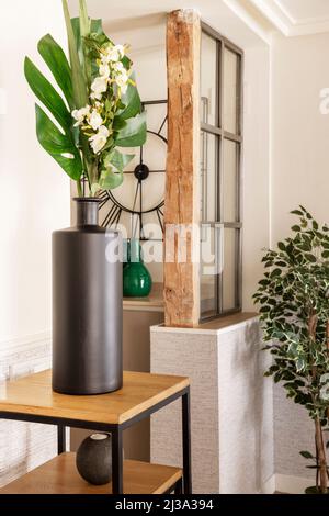 Corner of a house decorated with decorative plastic plants with vases and wooden details Stock Photo