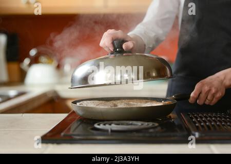 The chef prepares fresh pork steaks in the kitchen, home cooking menu. culinary recipes. restaurant menu. Delicious food, recipes and cooking Stock Photo