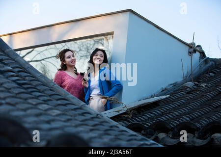 Chinese young ladies enjoying the traditional architectural landscape of Beijing's siheyuan at a floor-to-ceiling window - stock photo Stock Photo
