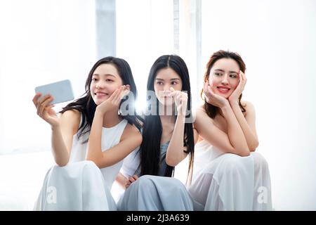 Fashionably dressed young women taking selfies with smart phone - stock photo