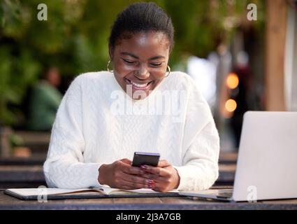 All the apps a student could want. Shot of a young woman using a smartphone while studying in a cafe. Stock Photo