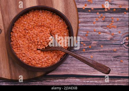 Lentil grains in wooden bowl and wooden spoon against wooden background Stock Photo