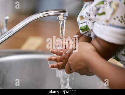 Keeping our hands clean. Shot of an unrecognizable child and parent washing their hands at home. Stock Photo