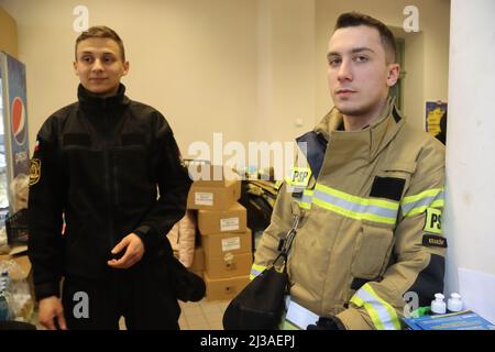 Przemysl, Poland. 3rd Apr, 2022. At the Przemysl station, close to the Ukraine/Polish border, city workers are now required to take shifts, to assist the Ukrainian refugee efforts. Here two Fireman man the information desk. Volunteers do anything needed from referrals to carrying luggage, babies, driving, security and offering a supportive ear, regardless of their job title. The Polish government and citizens are very concerned Putin will expand the war into their country. (Credit Image: © Amy Katz/ZUMA Press Wire) Stock Photo