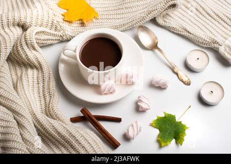 Autumn composition. Hot chocolate, warm wool sweater and autumn leaves, marshmallows and candles on a white background. flat lay, top view. Stock Photo