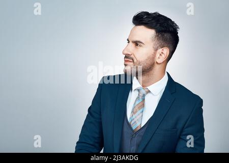 Greatnessdoes not approach him who is forever looking down. Studio shot of a handsome young businessman looking thoughtful against a grey background. Stock Photo