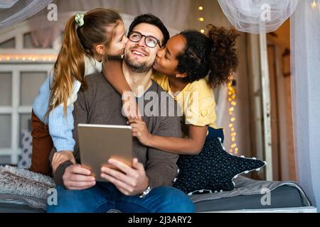 Multiethnic children and father having fun, playing on tablet at home Stock Photo
