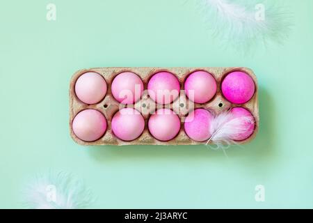 Minimal Easter concept. Easter elements, paper box with eggs in pink colors on pastel green background. Top view flat lay. Stock Photo
