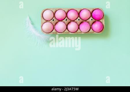 Minimal Easter concept. Easter elements, paper box with eggs in pink colors on pastel green background. Top view flat lay. Copy space. Stock Photo