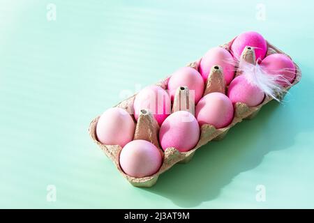 Minimal Easter concept. Easter elements, paper box with eggs in pink colors on pastel green background. Copy space. Stock Photo