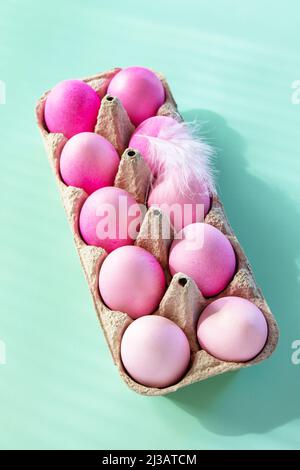 Minimal Easter concept. Easter elements, paper box with eggs in pink colors on pastel green background. Stock Photo