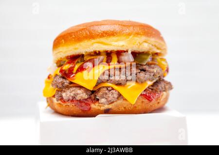 Double decker donut bun burger with beef patties and dressing on a takeaway box. Stock Photo