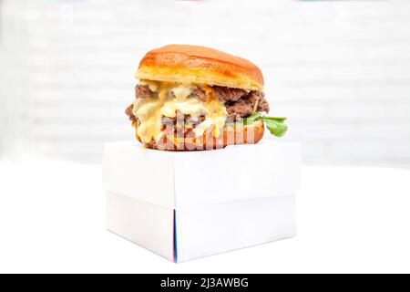 Double decker donut bun burger with beef patties and dressing on a takeaway box. Stock Photo