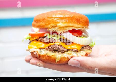 Double cheese beef burger with doughnut bun in the palm of a hand Stock Photo