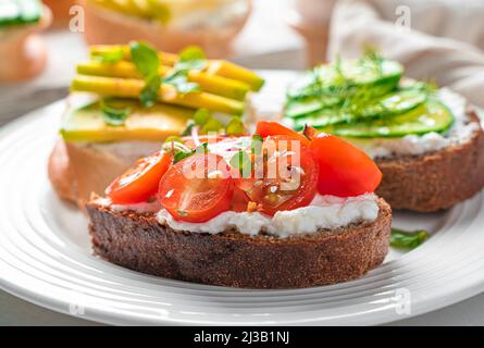 Sandwich with feta, cherry tomatoes, avocado and cucumber close-up. Healthy snacks. Crostini with feta. Stock Photo