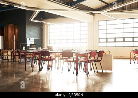 The office wont work unless we do. Shot of a table and chairs in an open plan office with no people. Stock Photo