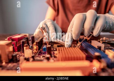 Engineer repairman holding hands in black gloves chip processor, CPU to insert into the socket of the computer motherboard. The concept of technology Stock Photo