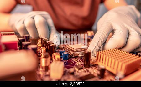 Engineer repairman holding hands in black gloves chip processor, CPU to insert into the socket of the computer motherboard. The concept of technology Stock Photo