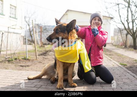 Little girl and German Shepherd with the flag of Ukraine. Stock Photo