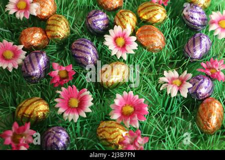 colorful easter eggs with pink flowers on grass background Stock Photo