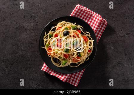 Spaghetti with vegetables(broccoli,tomatoes,peppers) on black background Stock Photo