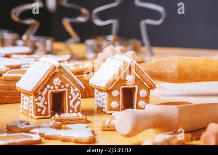 Christmas gingerbread houses and different shaped cookies with sugar icing on wooden table, close up with selective focus Stock Photo