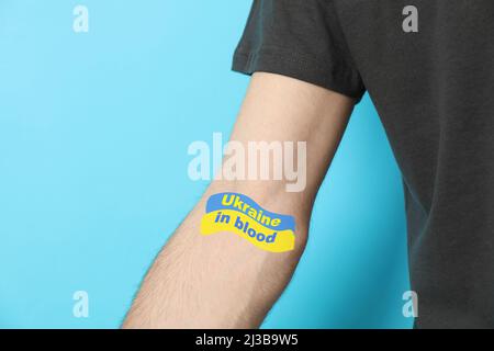 Man with text Ukraine in blood on hand, on blue background Stock Photo