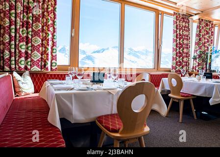 Elegant table setting beside window in hotel against snowcapped mountains Stock Photo