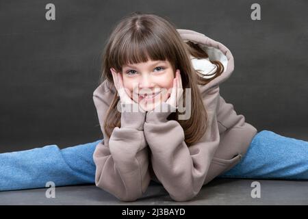 A beautiful middle school age girl in jeans looks at the camera and smiles. Nine-year-old girl of beautiful appearance. Stock Photo