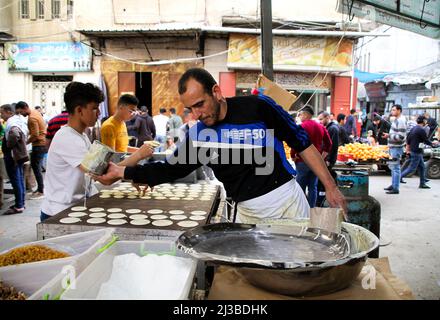 Gaza City, Gaza Strip, Palestine. 6th Apr, 2022. Gaza, Palestine. 06 April 2022. Palestinians prepare sweet pancakes or Qatayef in the Shujaiya market on the east of Gaza City during Ramadan. The fried pancakes are a traditional dessert in the Middle East especially during the holy month of Ramadan (Credit Image: © Ahmad Hasaballah/IMAGESLIVE via ZUMA Press Wire) Stock Photo