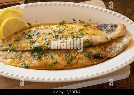 baked fish with lemon and herbs in dish Stock Photo