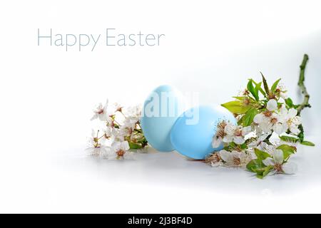 Two blue eggs and a branch of wild flowers on a white background, text Happy Easter, seasonal holiday greeting card, copy space, selected focus, narro Stock Photo