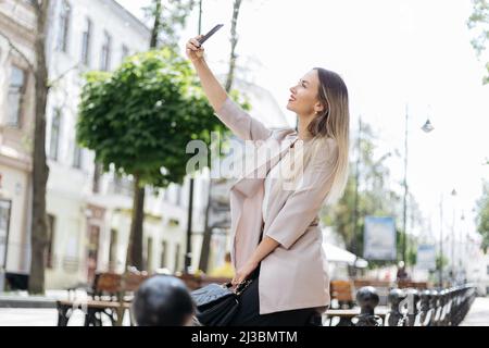 young woman taking a selfie while walking in the city. Stock Photo