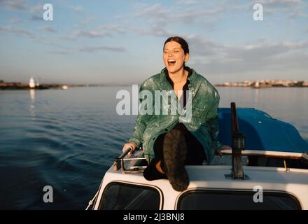 Smiling young woman sitting on motorboat Stock Photo