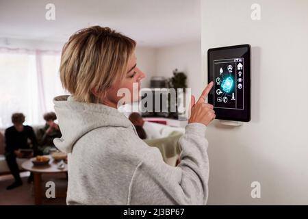 Woman using smart home application on wall mounted tablet Stock Photo