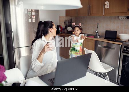Woman using laptop in kitchen Stock Photo