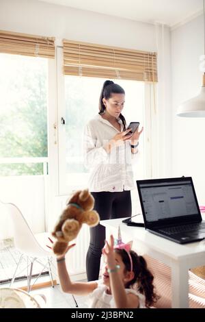 Woman in kitchen using cell phone Stock Photo
