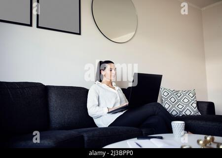 Woman on sofa using laptop Stock Photo