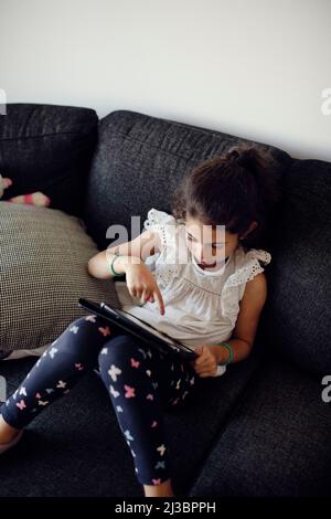 Girl using digital tablet on sofa Stock Photo