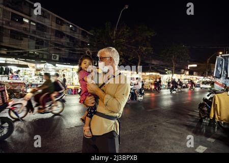Grandfather holding granddaughter in street at night Stock Photo