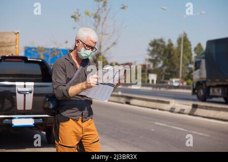 Senior man in face mask using map Stock Photo