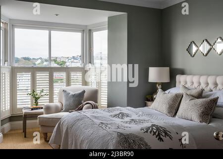 Sage green bedroom with armchair in window and view of St Ives, Cornwall, UK Stock Photo