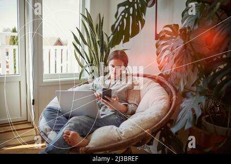 Woman using smart phone and laptop at home Stock Photo