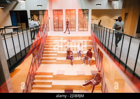 Business people sitting on stairs in office and working Stock Photo