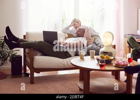 Smiling couple using laptop on sofa Stock Photo