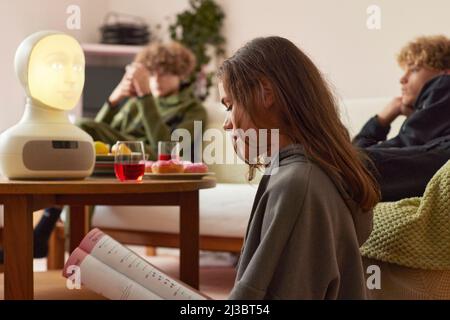 Girl doing homework with robotic voice assistant Stock Photo