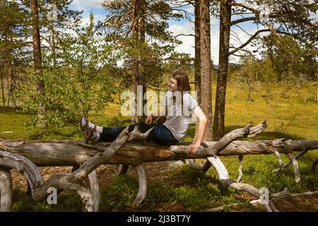 Young man sitting on fallen tree Stock Photo